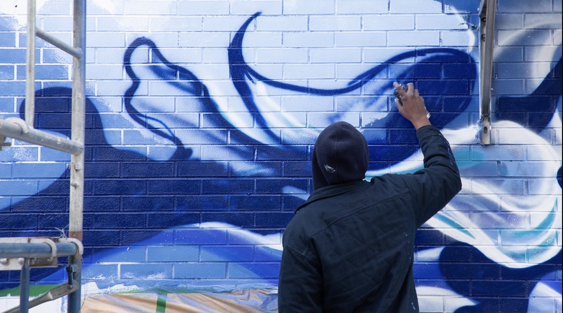 Large-scale mural in production on an industrial wall in Montréal